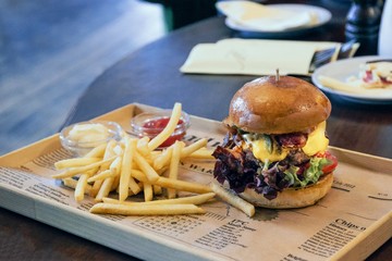 Burger with lettuce and bacon and french fries on the newspaper