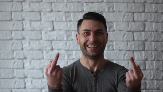 Bearded man showing middle fingers. Provocation defiance attitude and offensive indecent behavior concept. Casual hipster in grey t-shirt