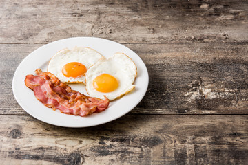 Fried eggs and bacon for breakfast on wooden table. Copyspace