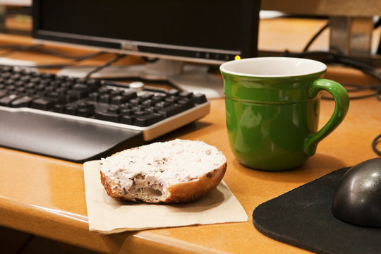 Coffee Cup and Bagel on a Desk