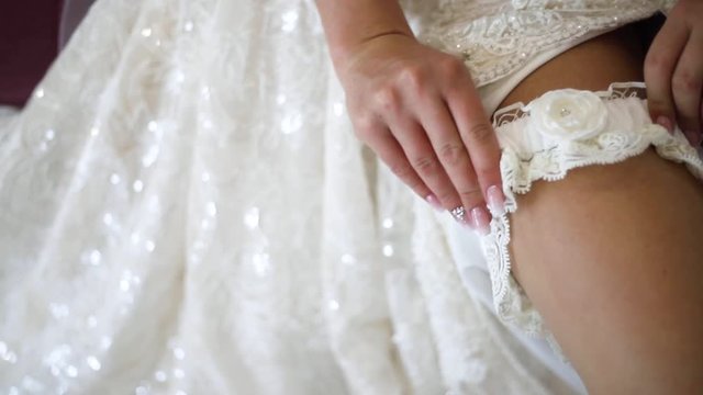 Bride put on beautiful openwork bandage on an elegant leg