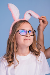 Beautiful young blond woman as easter bunny with rabbit ears on blue background.