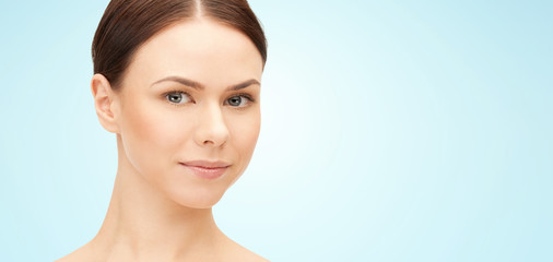 Fototapeta premium beauty and people concept - face of beautiful young woman over blue background