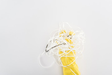 Cropped view of man in yellow rubber gloves holding paper strips on grey background