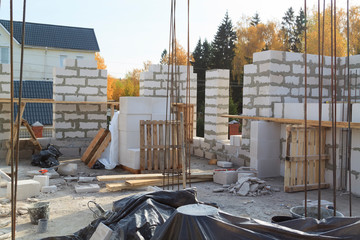 view of laying walls of first floor, fittings for filling supporting columns. Construction of country house made of foam blocks