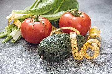 Lettuce greens, red tomatoes, avocados and body tape. Background about diets and weight loss, vegetarian cuisine, weight loss