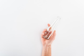Cropped view of man holding empty glass bottle on grey background