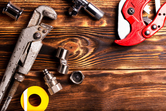 Plumbing tools and fixtures on a dark wooden background. Close-up