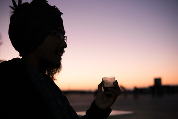 Young Asian Bearded Tourist man with Dreadlocks and scarf on head Drinking Morroccan coffee in...