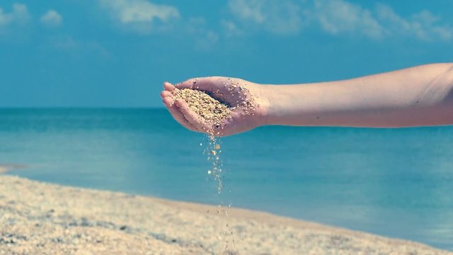 Seashore sand pouring from Woman hand,  marine slow motion