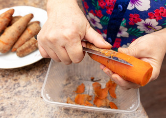 Woman cuts carrots with a knife in the kitchen