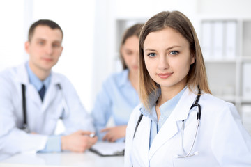 Young beautiful female doctor smiling  on the background with patient  in hospital