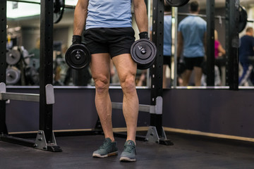 Attractive man holding heavy dumbbell at the gym.
