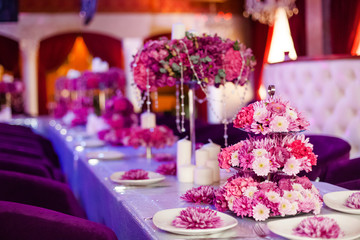 Wedding party table flowers and white candles on the table. Pink pions and wite chrysanthemums bouqet with shining decor