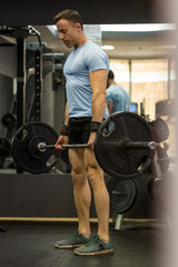 Fototapeta na wymiar Image of a muscular man pulling a heavy barbell at the gym.