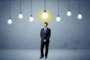 Fototapeta premium Handsome businessman in an empty space with bulbs above and uninspired face 