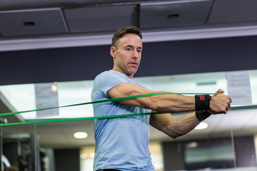 Man doing side-to-side chops exercise with elastic band at the gym.