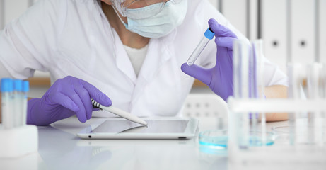 Close-up of professional female scientist in protective eyeglasses making experiment with reagents...