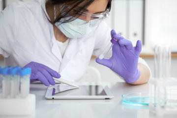 Close-up of professional female scientist in protective eyeglasses making experiment with reagents...