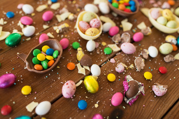 Fototapeta na wymiar easter, sweets and confectionery concept - close up of chocolate eggs and candy drops on wooden table