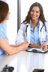 Doctor and  happy patient  talking while sitting at the desk. The physician or therapist discussing healthy lifestyle. Health care, medicine and patient service concept