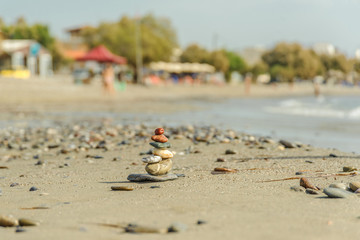 Pebbles stacked in a pyramid on the beach against the backdrop of the sea and the sun