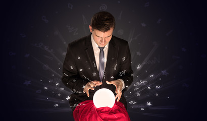 Gorgeous businessman looking to inspiration in a magic ball in his lap and doodle concept
