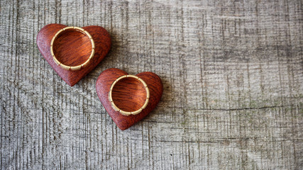 Wedding rings and red heart on wooden background