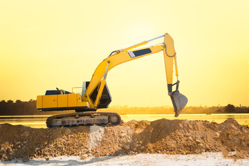 Industrial excavator working on construction site to clear the land of sand and soil at sunset © yupachingping