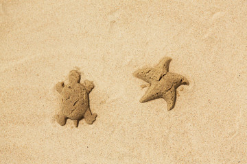 toys, childhood and vacation concept - sand shapes made by turtle and starfish molds on summer beach