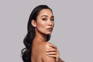 Sensuality. Beautiful young woman looking at camera while standing against grey background