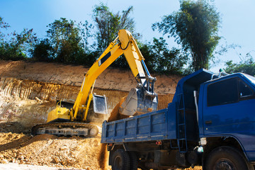 Industrial excavator and truck working on construction site to clear the land of sand and soil