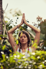 Young woman practicing yoga - meditation in the tropical garden.