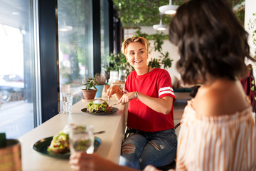 food and people concept - female friends eating at restaurant or cafe