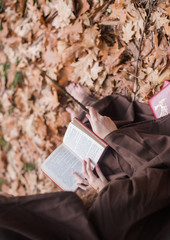 Mujer leyendo en otoño disfrazada de mago con varita
