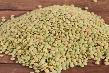 a bunch of green lentils on a wooden background