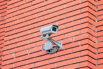 CCTV security camera on the red brick stone wall