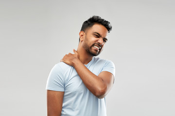 health problem and people concept - unhealthy indian man suffering from neck pain over grey background