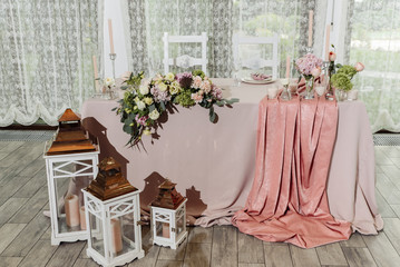 Wedding table serving. Wedding classic decor. Wedding presidium for the newlyweds. Beautiful decor with pastel roses, candle and greenery