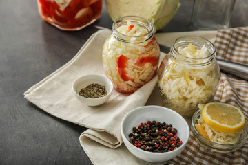 Glass jars with fermented vegetables and spices on table