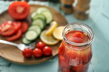 Glass jar with fermented tomatoes on table