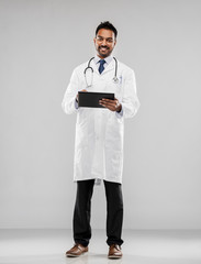medicine, technology and healthcare concept - smiling indian male doctor in white coat with tablet computer and stethoscope over grey background
