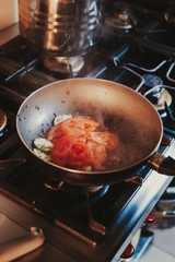 Tomato and cucumber cooking in frying pan on the stove