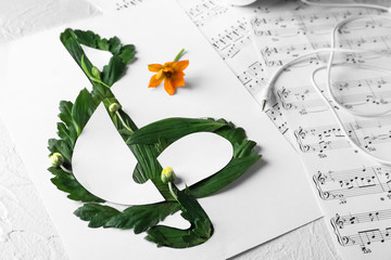Violin clef made of green leaves and note sheets on table