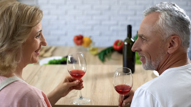 Romantic aged couple with wine glasses at home date, happy marriage, aperitif