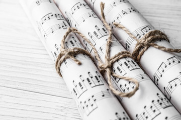 Rolled music sheets on white wooden table, closeup