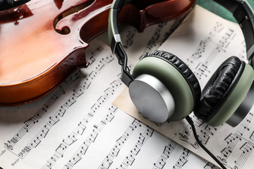 Violin, headphones and music sheets on table