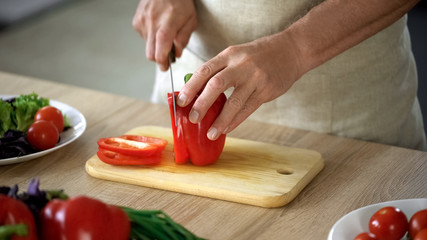 Male chef cutting fresh red pepper, cooking organic dinner salad, culinary show