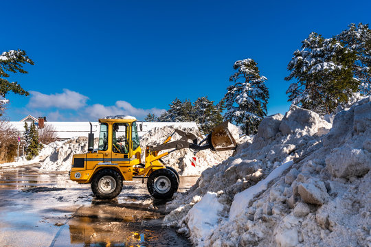 Bagger baggert Schneemassen auf einem Parkplatz