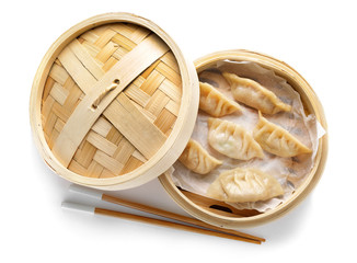 Bamboo steamer with tasty Japanese gyoza on white background
